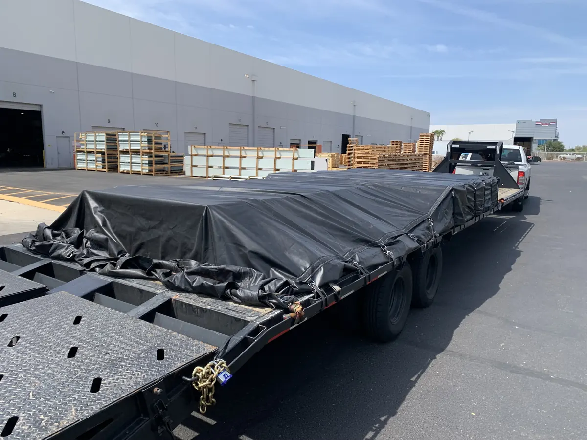 Full-length black tarp over a load at a warehouse dock