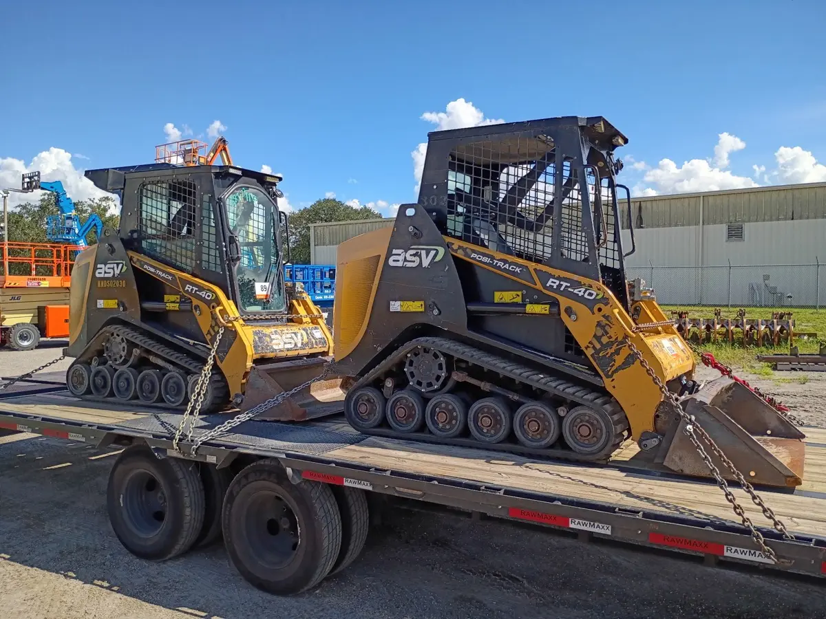 Two ASV compact track loaders chained down on the flatbed