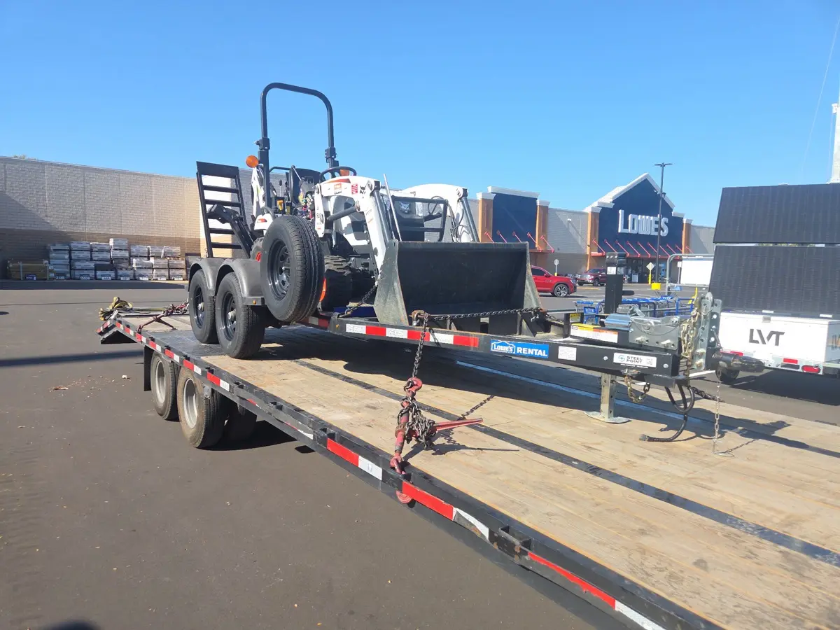 Compact tractor with loader on the trailer at a store pickup